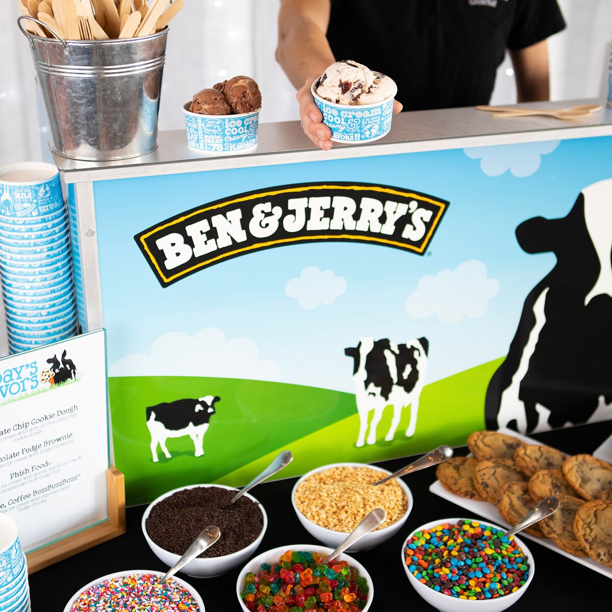An ice cream catering cart with toppings on a table